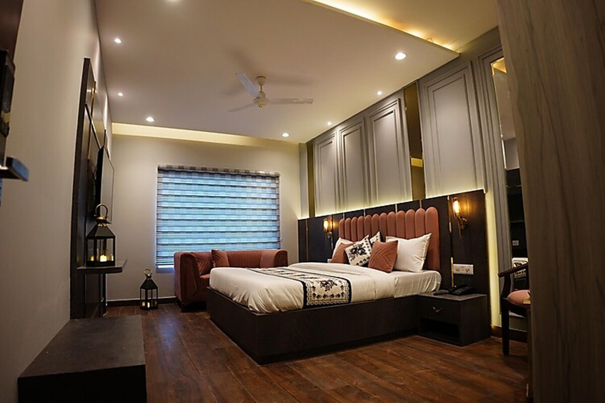 A modern bedroom with a large bed, built-in cabinets, a ceiling fan, and a window with blinds.