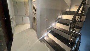 Een modern interieur met een trap, een muur met decoratieve panelen en een deur naar een andere kamer.