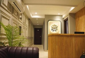 A reception area with a wooden reception desk, a potted plant, and a modern interior design. - Narison Hotel By Divud Ecom (Amritsar)