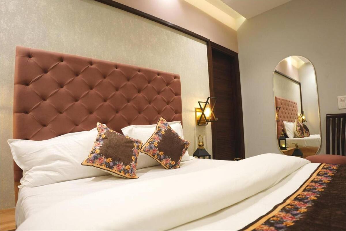 A neatly made bed with a tufted headboard, two floral pillows, and a decorative throw.