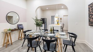A modern dining area with a glass table, black chairs, and a central island with a sink and decorative items.