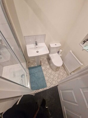 A bathroom with a white sink, toilet, and patterned floor tiles.