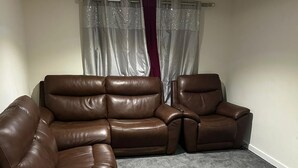 A living room with a sectional sofa, a single armchair, and a small table. - Full house- Free Parking, Wifi, and appliances to make your stay comfortable. (Hull)