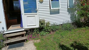 Ein Wohnmobil mit offener Tür, durch die ein Schlafzimmer mit Bett und Fenster zu sehen ist.