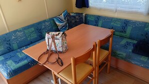Ein gemütliches Zimmer mit einem Holztisch und Stühlen, einer gemusterten Couch und einer Dekokiste auf dem Tisch.