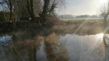 A calm river with trees and a distant building.