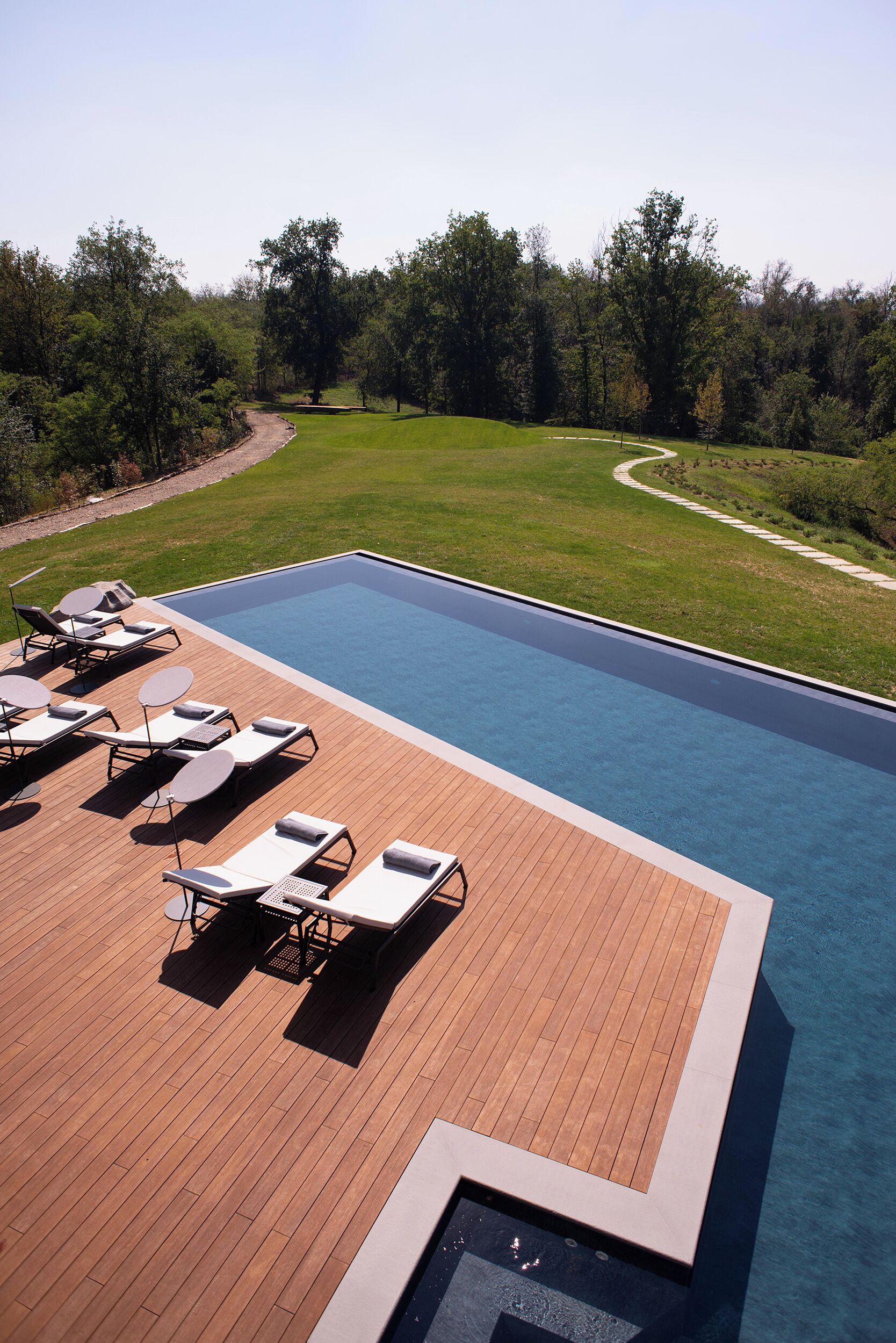 Una piscina con sillas de descanso y un muelle de madera.