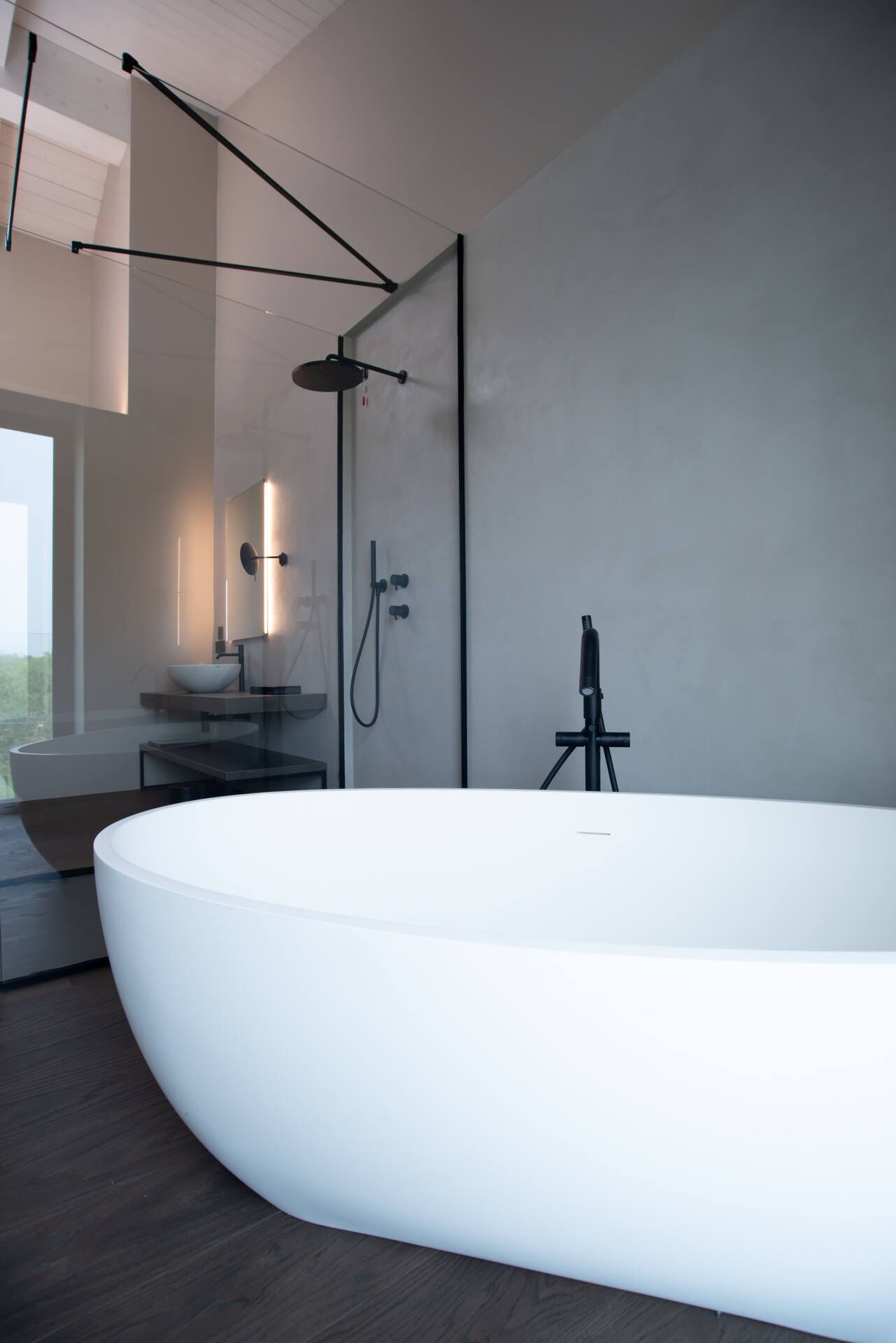 A modern bathroom with a large freestanding bathtub, a glass shower enclosure, and a minimalist sink area.