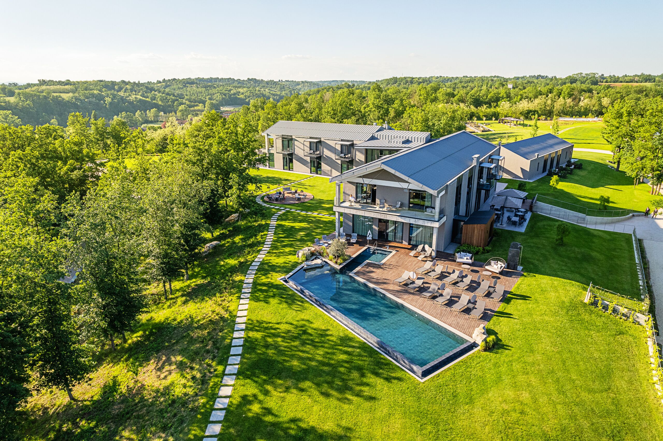 Une maison moderne dotée d’une piscine, entourée d’une végétation luxuriante et d’une pelouse bien entretenue.