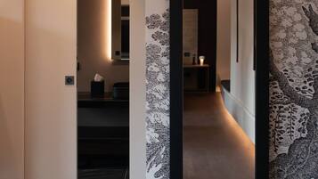 A hallway with a large mirror reflecting a modern interior. A plush white pillow is visible in the foreground.