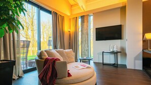 Una sala de estar moderna con un sofá redondo, un televisor de pantalla plana y una mesita de noche con lámpara.