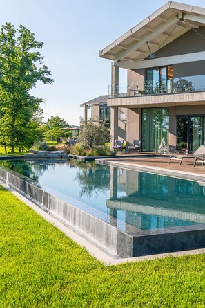 A modern house with a swimming pool, a covered patio, and a view of the surrounding greenery. - Le Cattedrali Relais by Laqua Collection (Asti)