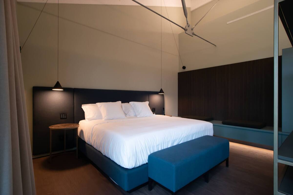 A modern bedroom with a large bed, bedside tables, and a bench.