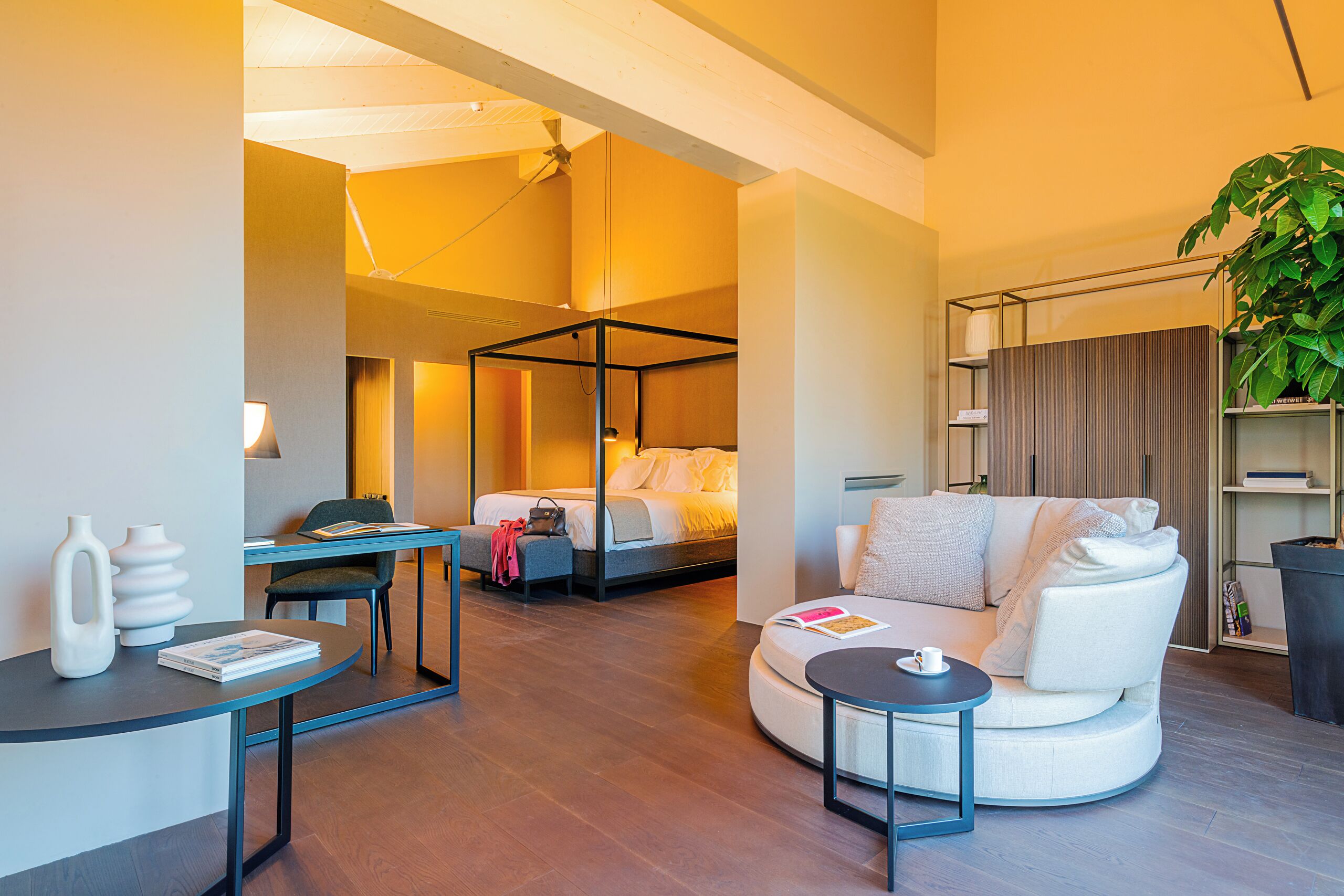 Una habitación de hotel moderna con una cama abatible, un sofá, una pequeña mesa y una estantería.