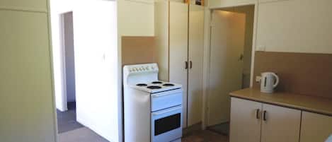 Una cocina compacta con estufa blanca, armarios y una cafetera en la encimera.