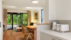 A modern kitchen with a wooden dining table, chairs, and a built-in oven.