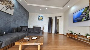 Una sala de estar moderna con un sofá gris, una mesa de centro de madera y un televisor montado en la pared.