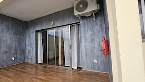 Una habitación con puerta de vidrio corredera, ventilador de techo y extintor de incendios en la pared.