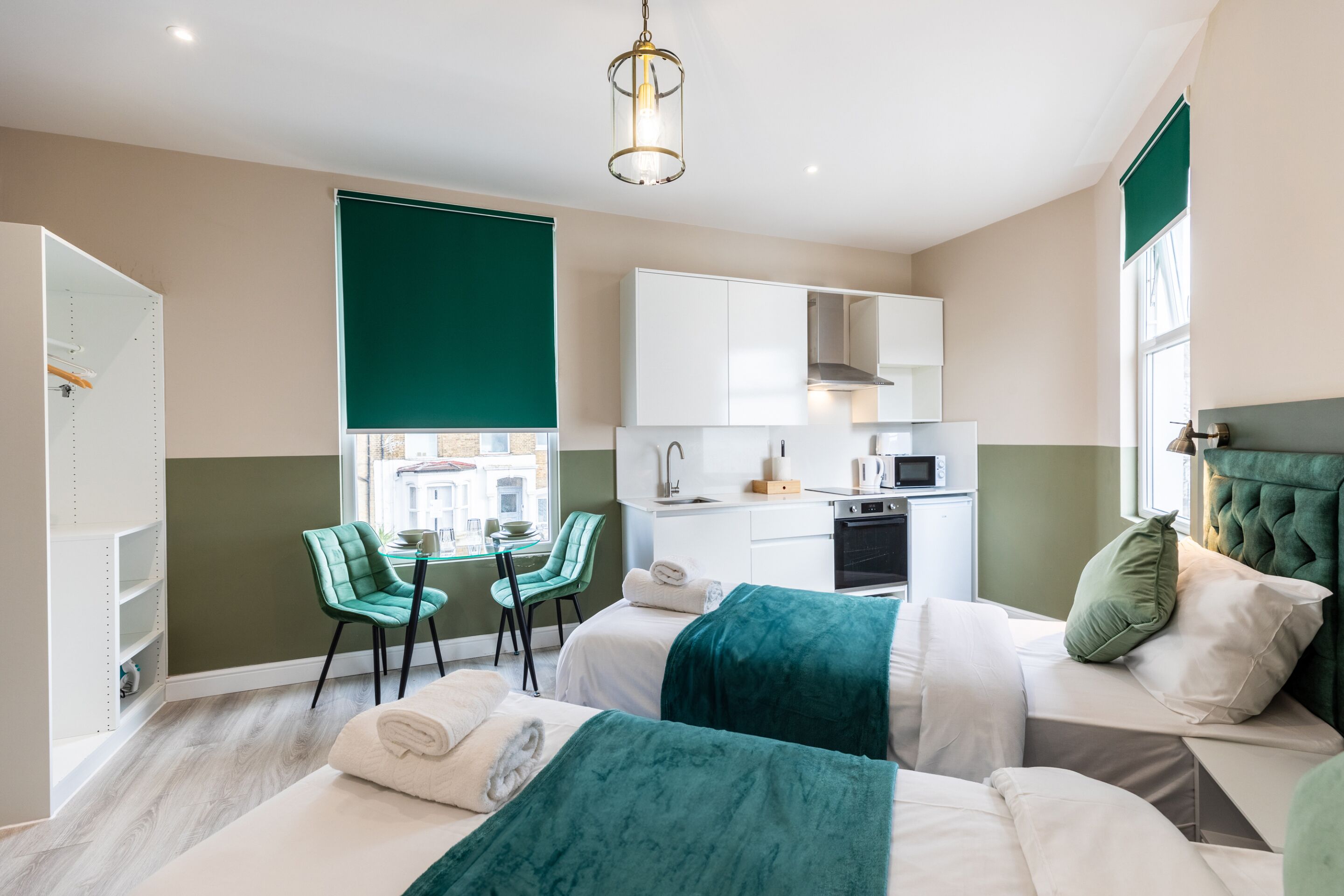 Een moderne hotelkamer met een bed, een bureau, een stoel en een kitchenette.