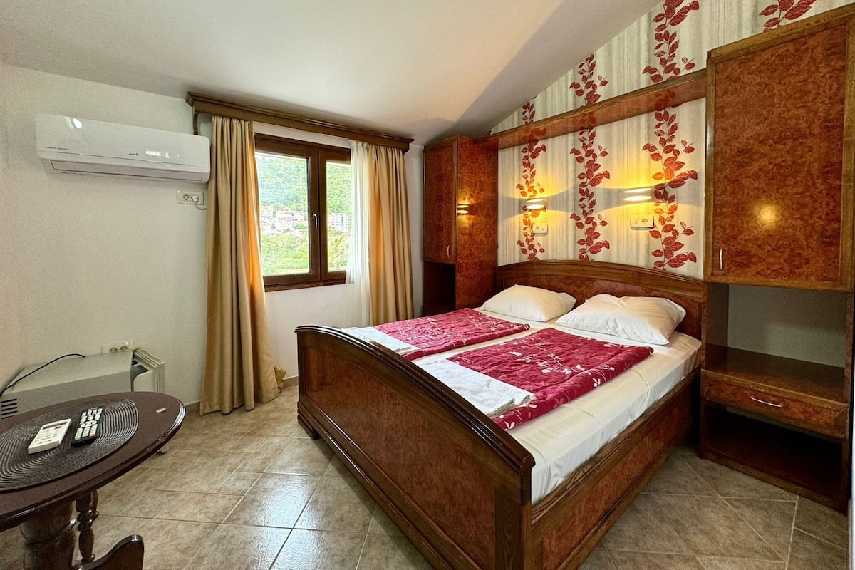 Une chambre à coucher avec un lit en bois, un bureau avec une chaise et une fenêtre avec des rideaux.