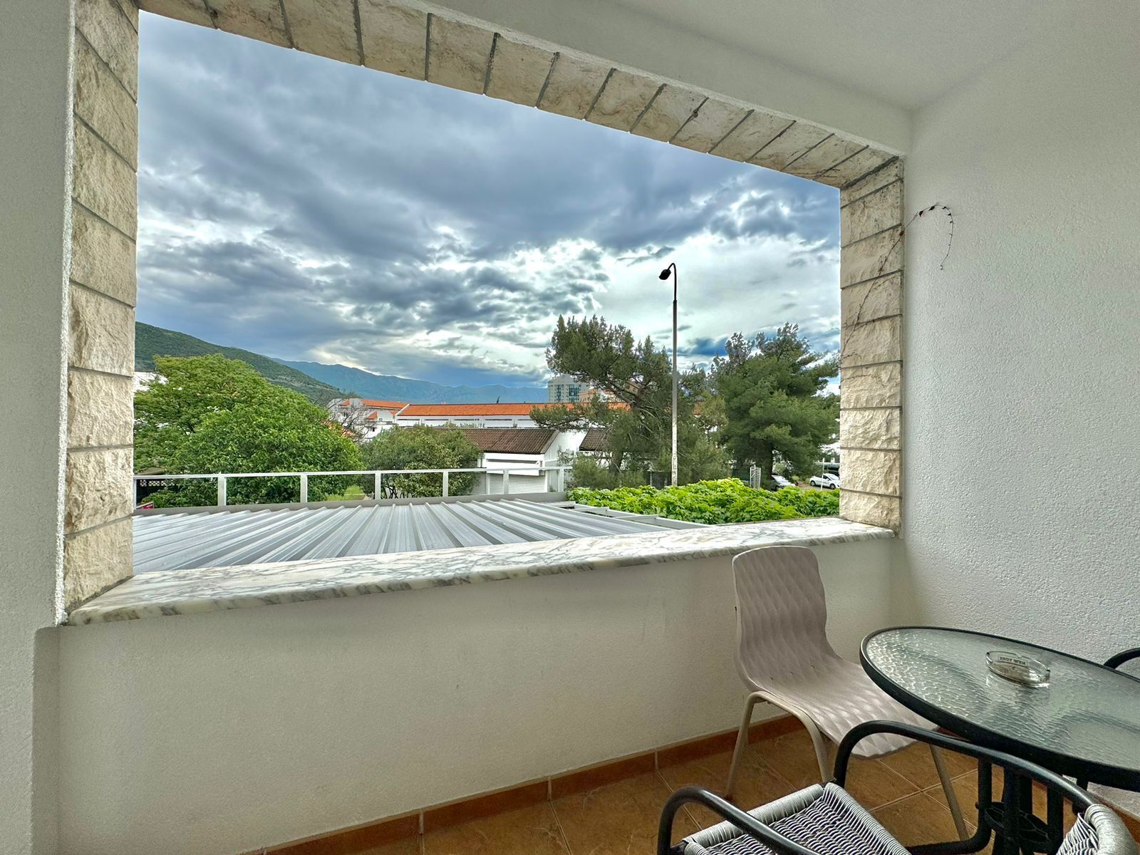Uma varanda com vista para uma cidade, uma mesa e uma cadeira.