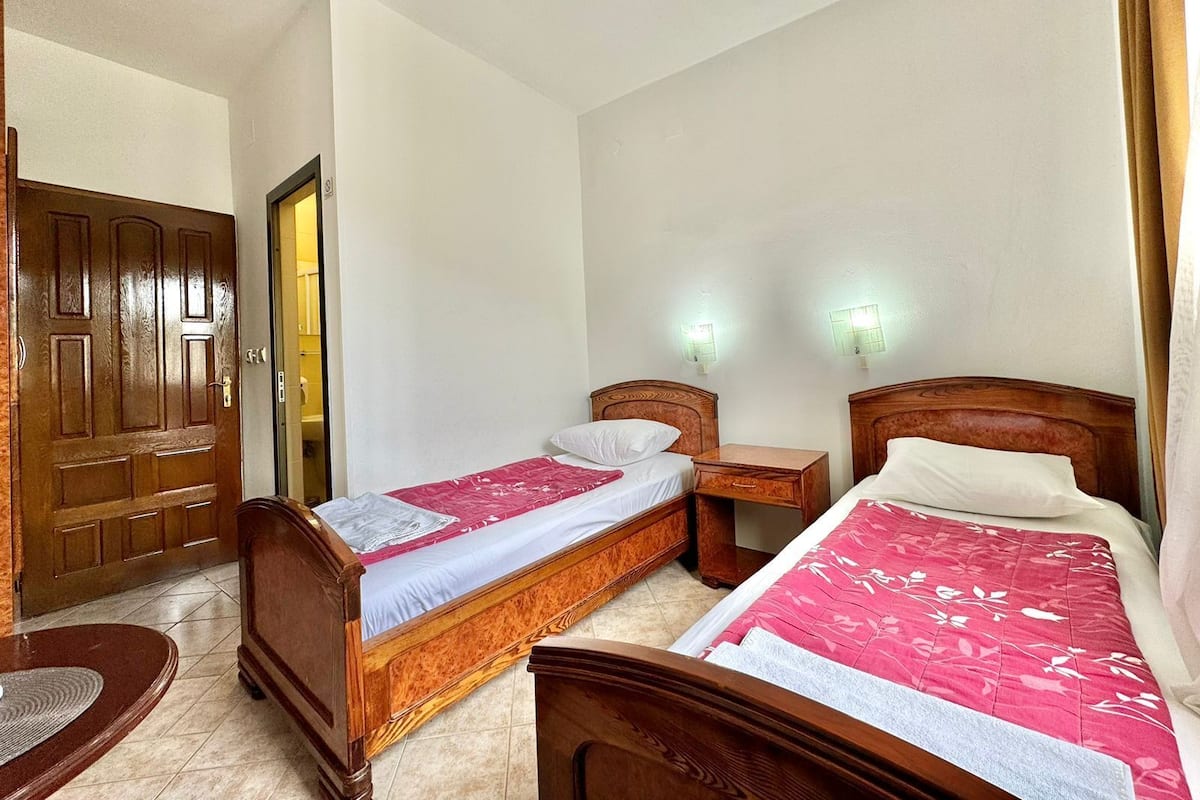 Une chambre à coucher avec deux lits en bois, une table de chevet en bois, une chaise en bois et une porte en bois.