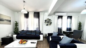 A modern living room with a sofa, coffee table, and a dining area. - STAY Villa Princess (Protaras)