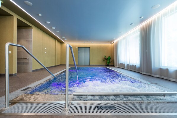 An indoor swimming pool with a blue water feature, a metal ladder, and a potted plant. - Residenza Du Lac (Paradiso)
