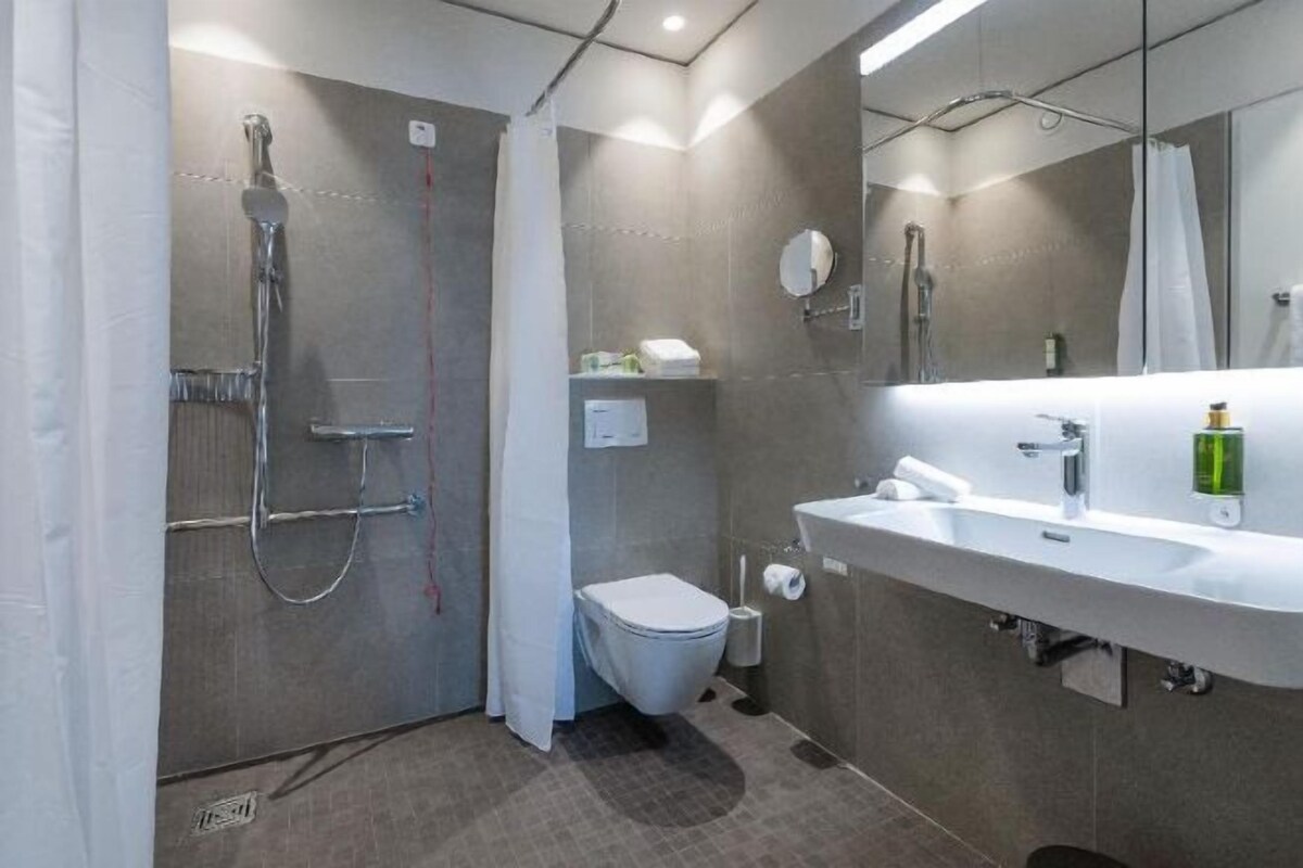 A modern bathroom with a shower, toilet, and sink.