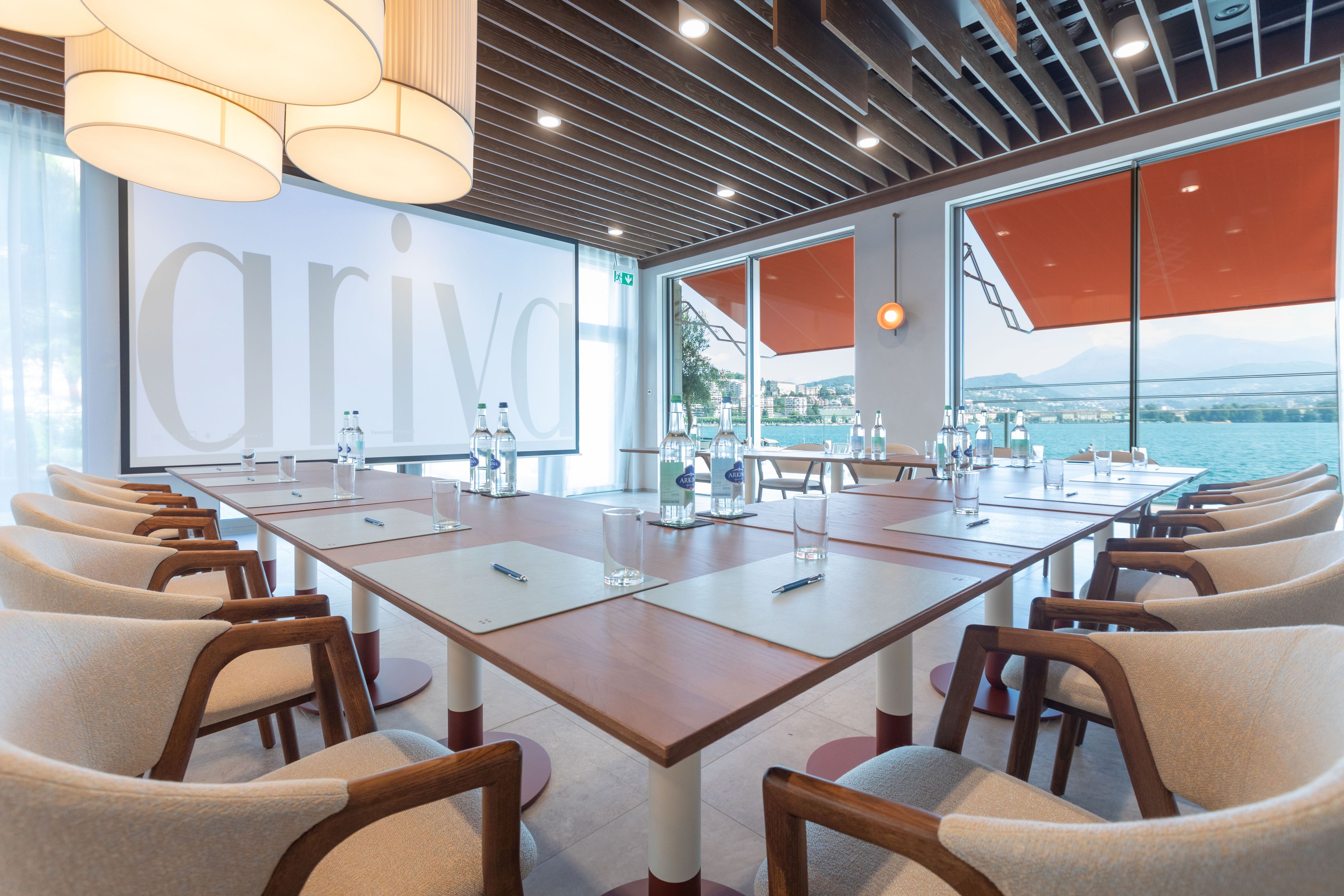 A conference room with a long table, chairs, and a view of a body of water.
