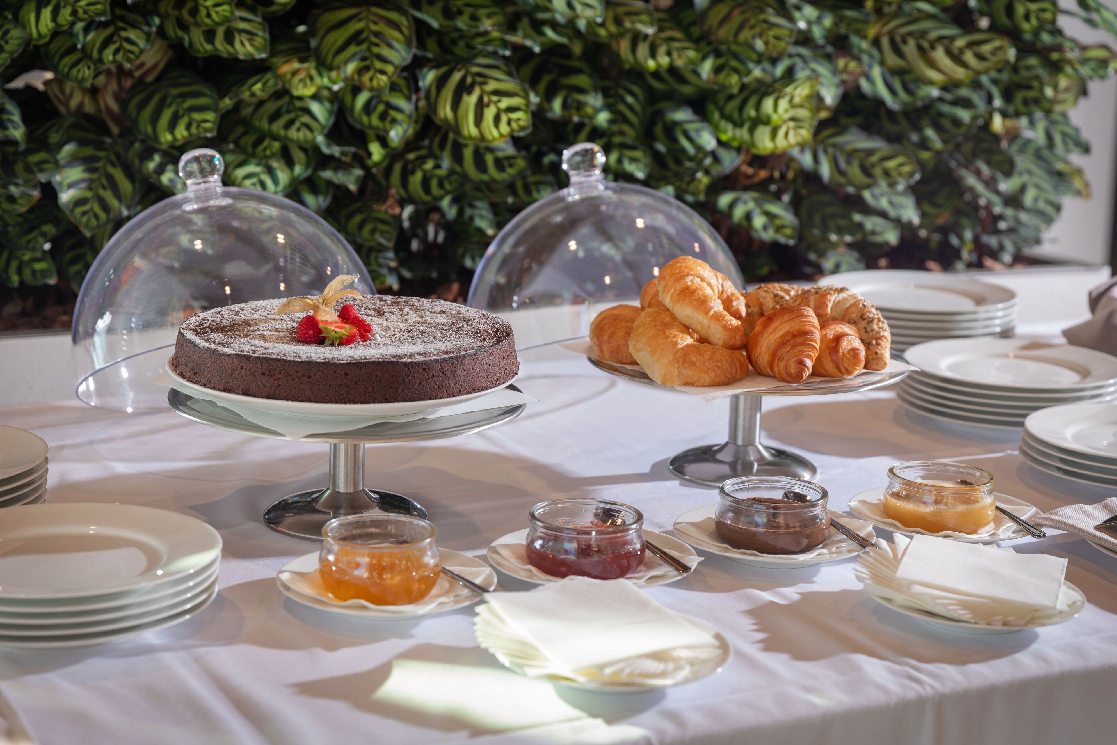 Ein Büfett mit Schokoladenkuchen, Croissants und verschiedenen Marmeladen und Aufstrichen.