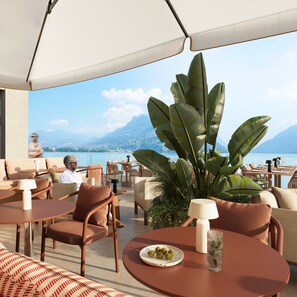 A terrace with outdoor seating, a view of the sea, and a mountain in the background. - Residenza Du Lac (Paradiso)