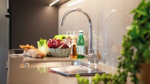 A modern kitchen with a stainless steel sink, a bowl of salad, and a bottle of olive oil. - Residenza Du Lac (Paradiso)