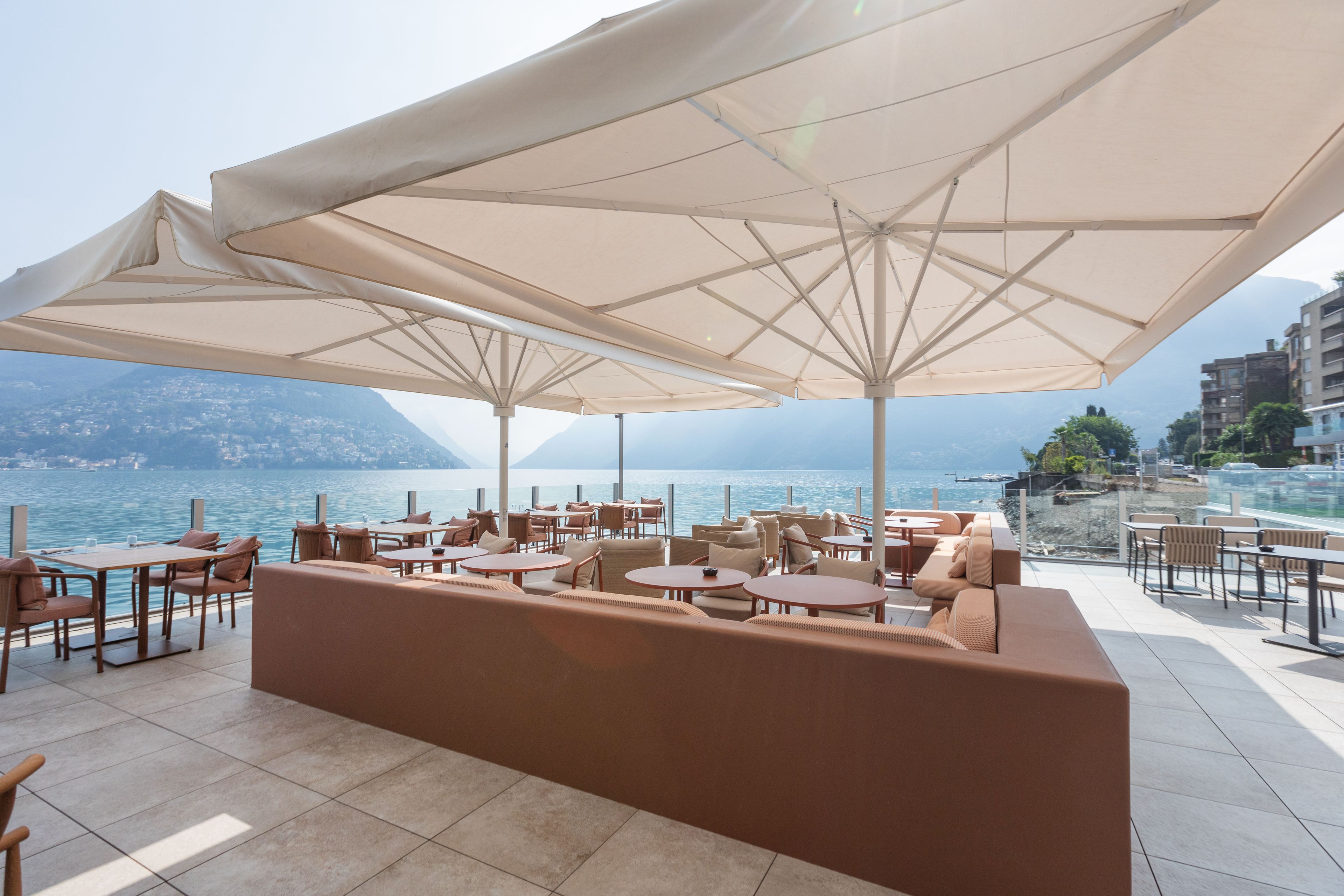 Eine Terrasse mit Sitzgelegenheiten im Freien, großen Sonnenschirmen und Meerblick.