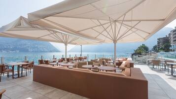 Eine Terrasse mit Sitzgelegenheiten im Freien, großen Sonnenschirmen und Meerblick.
