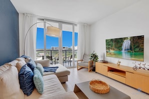 Una sala moderna con sofá, televisor y balcón con vistas a la ciudad.
