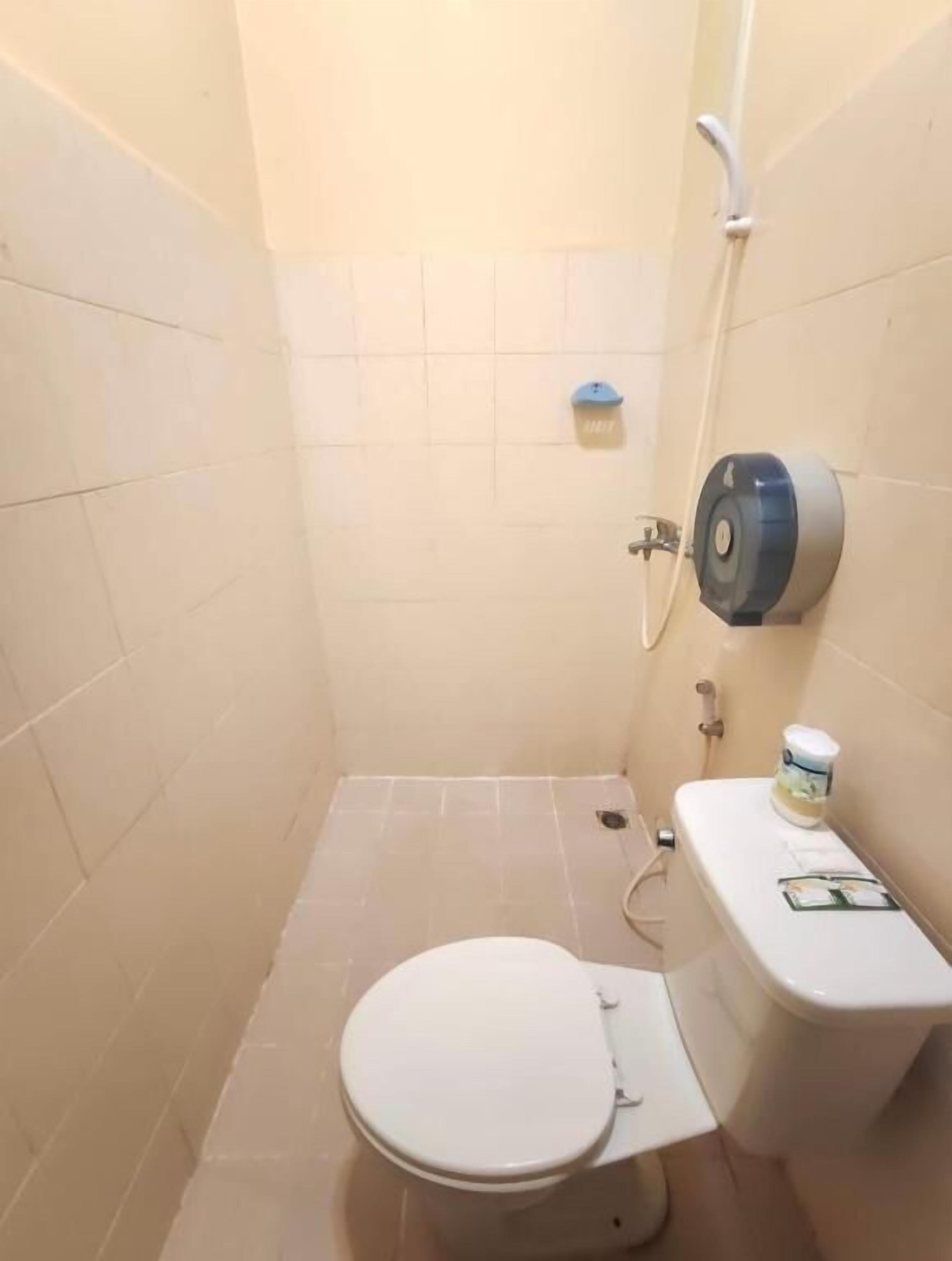 Baño pequeño y funcional con inodoro, secador de manos y dispensador de toallas de papel.