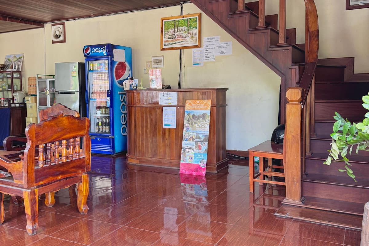 A reception area with a wooden desk, a Pepsi refrigerator, a wooden chair, a staircase, and a tiled floor.