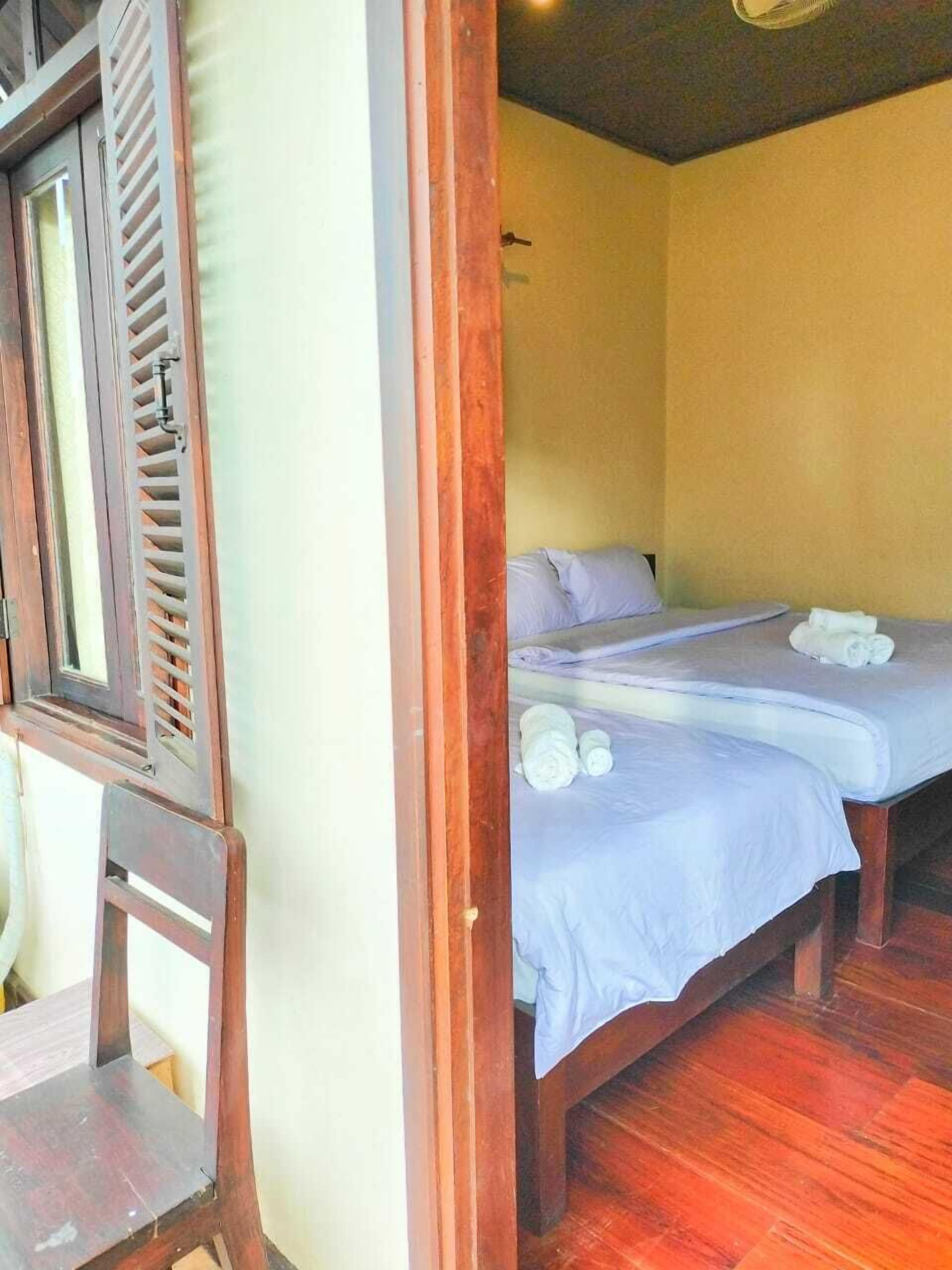 Una habitación con dos camas, muebles de madera y una ventana con contraventanas.