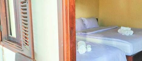 Una habitación con dos camas, muebles de madera y una ventana con contraventanas.