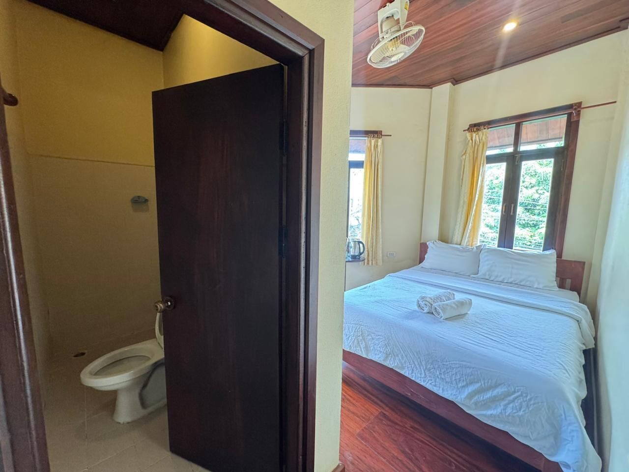 A room with a bed, a wooden door, and a toilet.