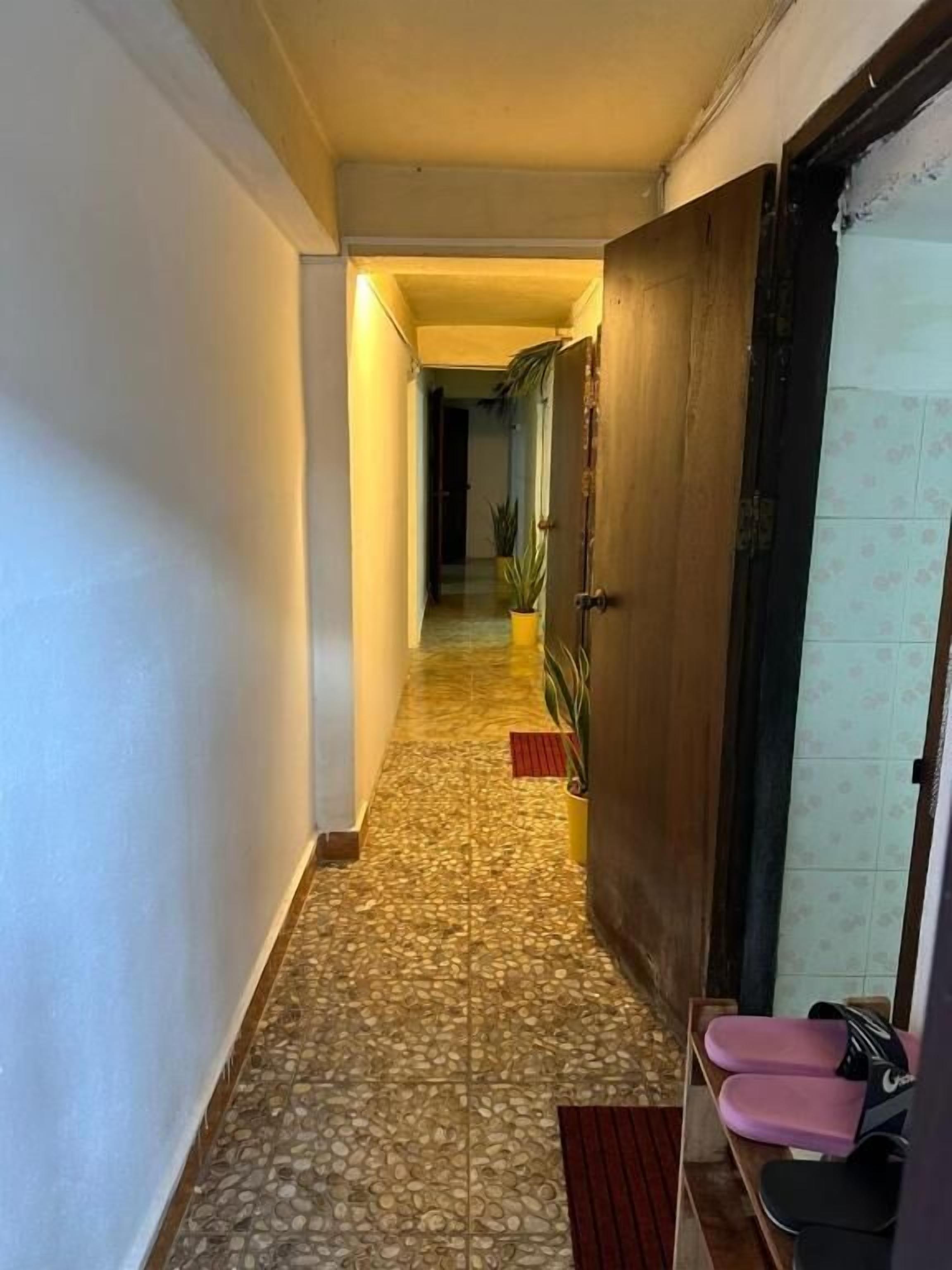 A hallway with patterned flooring, a wooden door, and a bench with seating.
