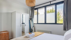 Un dormitorio con cama, armario, radiador y ventana con cortinas.