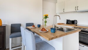 Una cocina moderna con encimera de madera, dos taburetes de bar, una cafetera y un jarrón con flores.