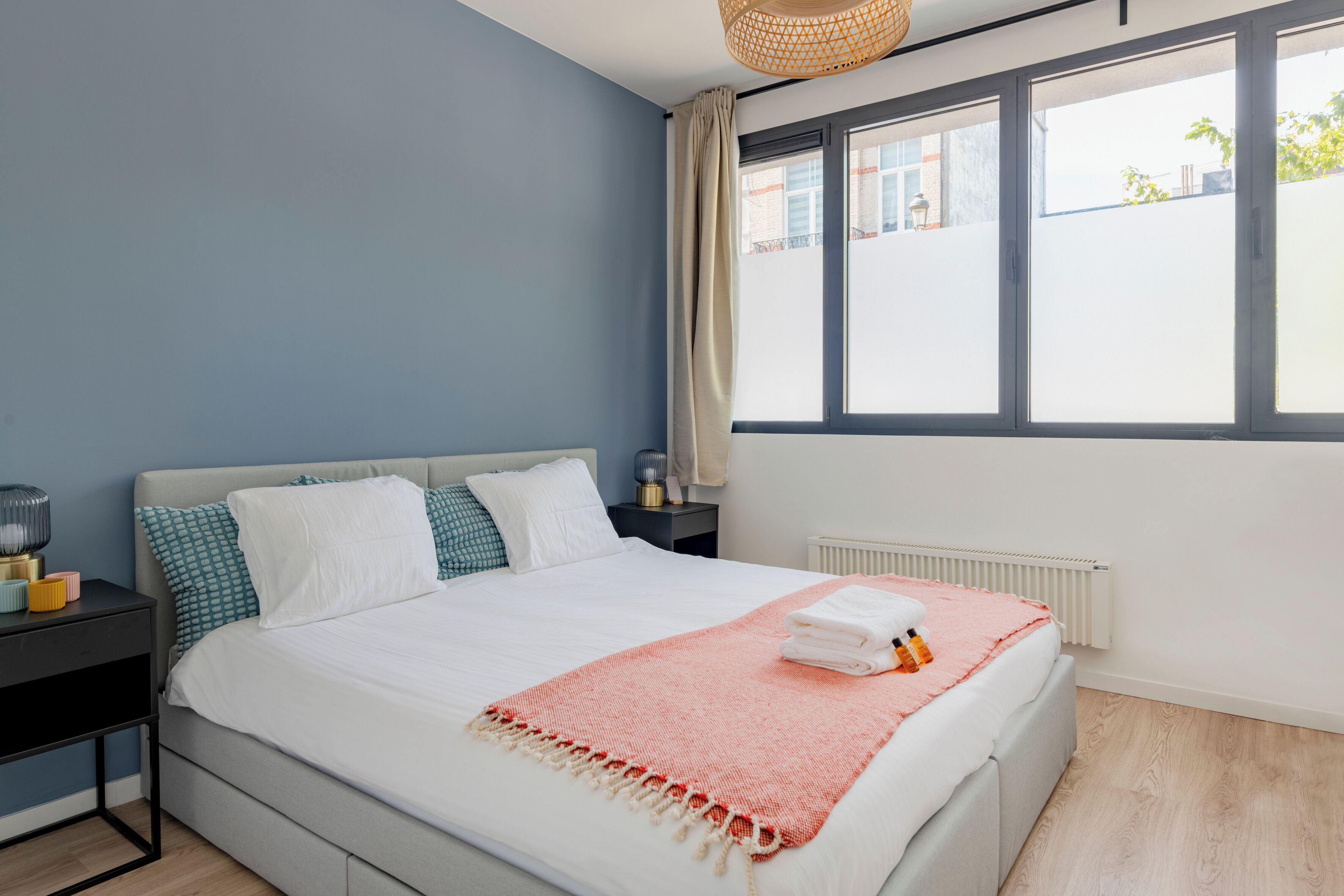 Een slaapkamer met een bed, nachtkastjes, een raam en een radiator.