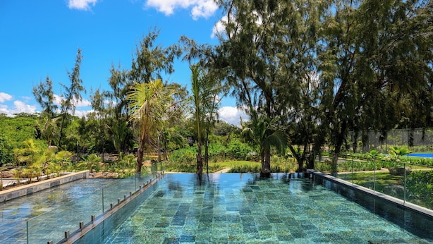 A rectangular infinity pool with clear water, surrounded by lush greenery and trees. - Ocean Grand Gaube with LOV (Grand Gaube)