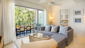 A modern living room with a grey sofa, patterned cushions, a wooden chair, and a dining area with a table and chairs. - Ocean Grand Gaube with LOV (Grand Gaube)