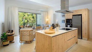 A modern kitchen with a central island, wooden cabinetry, and a stainless steel refrigerator. - Ocean Grand Gaube with LOV (Grand Gaube)