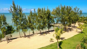 A beach with clear turquoise water, a sandy shore, and a line of trees. - Ocean Grand Gaube with LOV (Grand Gaube)