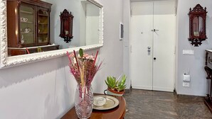 A hallway with a white door, a mirror, and a wooden cabinet. - 4bnb - Leone IV Apartment (Rome)